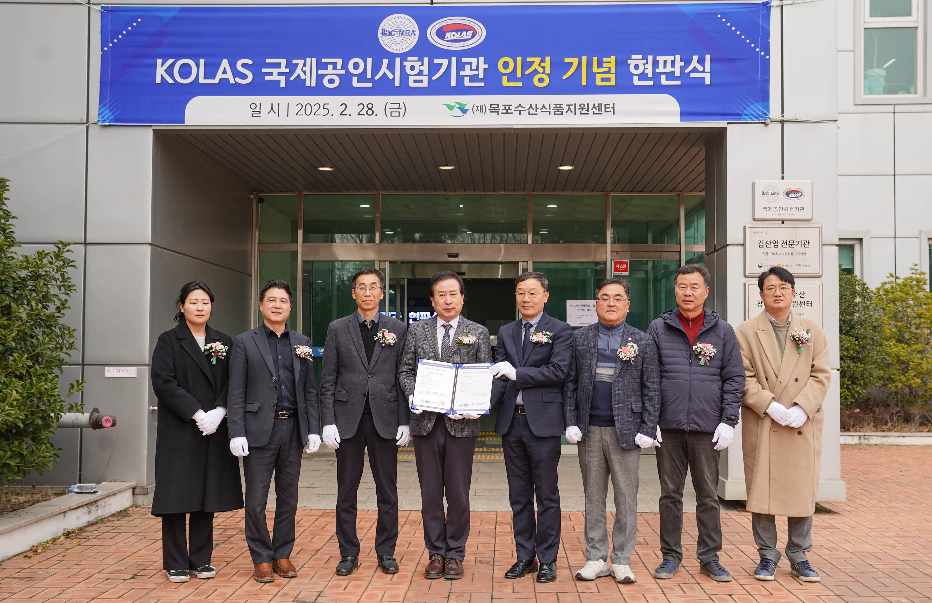 현판식 현장 앞에서 박홍률 목포시장을 비롯한 관계자들이 서서 단체 사진을 촬영하고 있음. 배경에는 건물 출입문과 파란색 현수막이 있음.
현수막 문구:
'KOLAS 국제공인시험기관 인정 기념 현판식
일 시 | 2025. 2. 28. (금)
(재)목포수산식품지원센터'