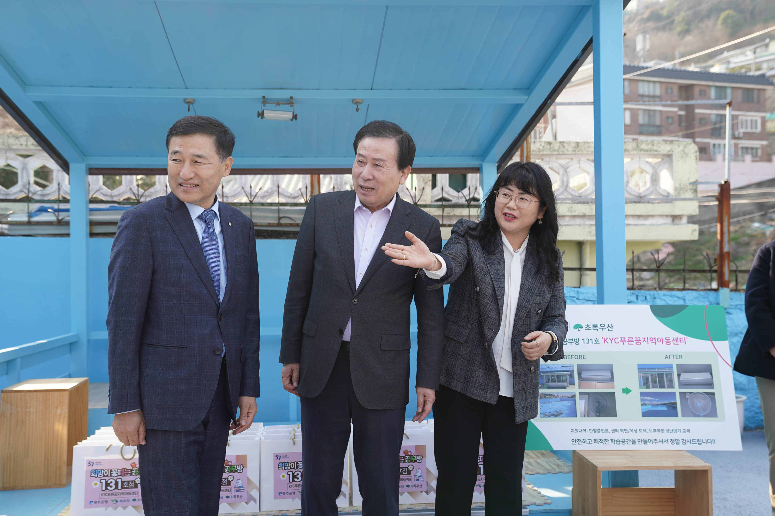 파란색 구조물 앞에 박홍률 목포시장을 비롯한 세 명의 사람이 서있는 모습. 제일 오른쪽에는 체크무늬 재킷을 입은 관계자가 손을 들어 어딘가를 가리키고 있다.