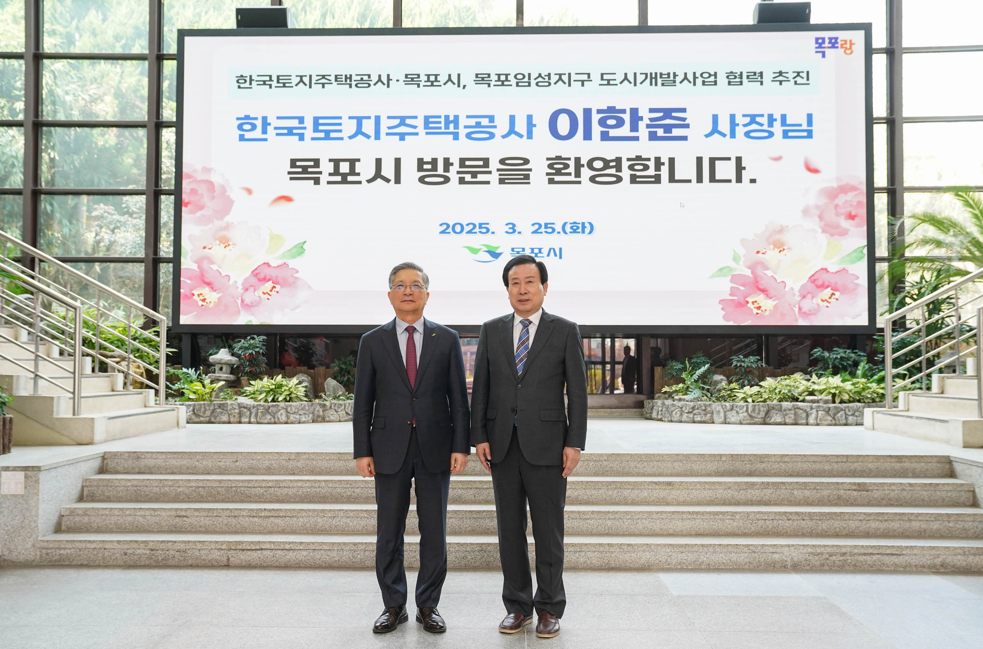 대형 전광판 앞에서 양복을 입은 박홍률 목포시장과 이한준 한국토지주택공사 사장이 나란히 서있는 모습. 전광판에는
'한국토지주택공사·목포시, 목포임성지구 도시개발사업 협력 추진
한국토지주택공사 이한준 사장님
목포시 방문을 환영합니다. 2025.3.25.(화) 목포시' 라고 적혀있음