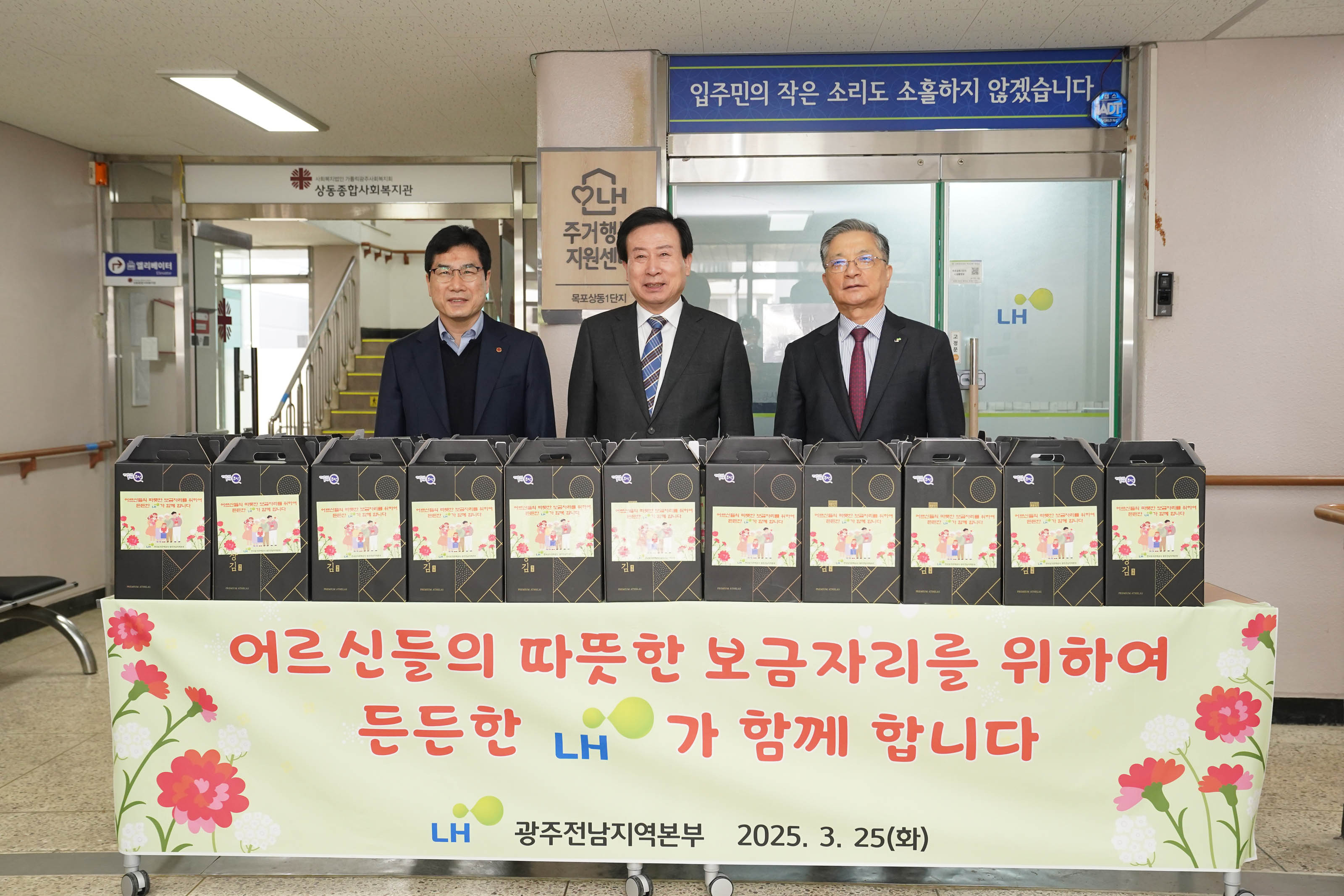 박홍률 목포시장과 이한준 한국주택토지공사 사장, 그리고 관계자가 선물 상자 앞에 서서 사진을 찍고 있다. 테이블 천에는 다음과 같은 문구가 적혀 있다:
'어르신들의 따뜻한 보금자리를 위하여 든든한 LH가 함께 합니다
LH 광주전남지역본부 2025. 3. 25(화)'