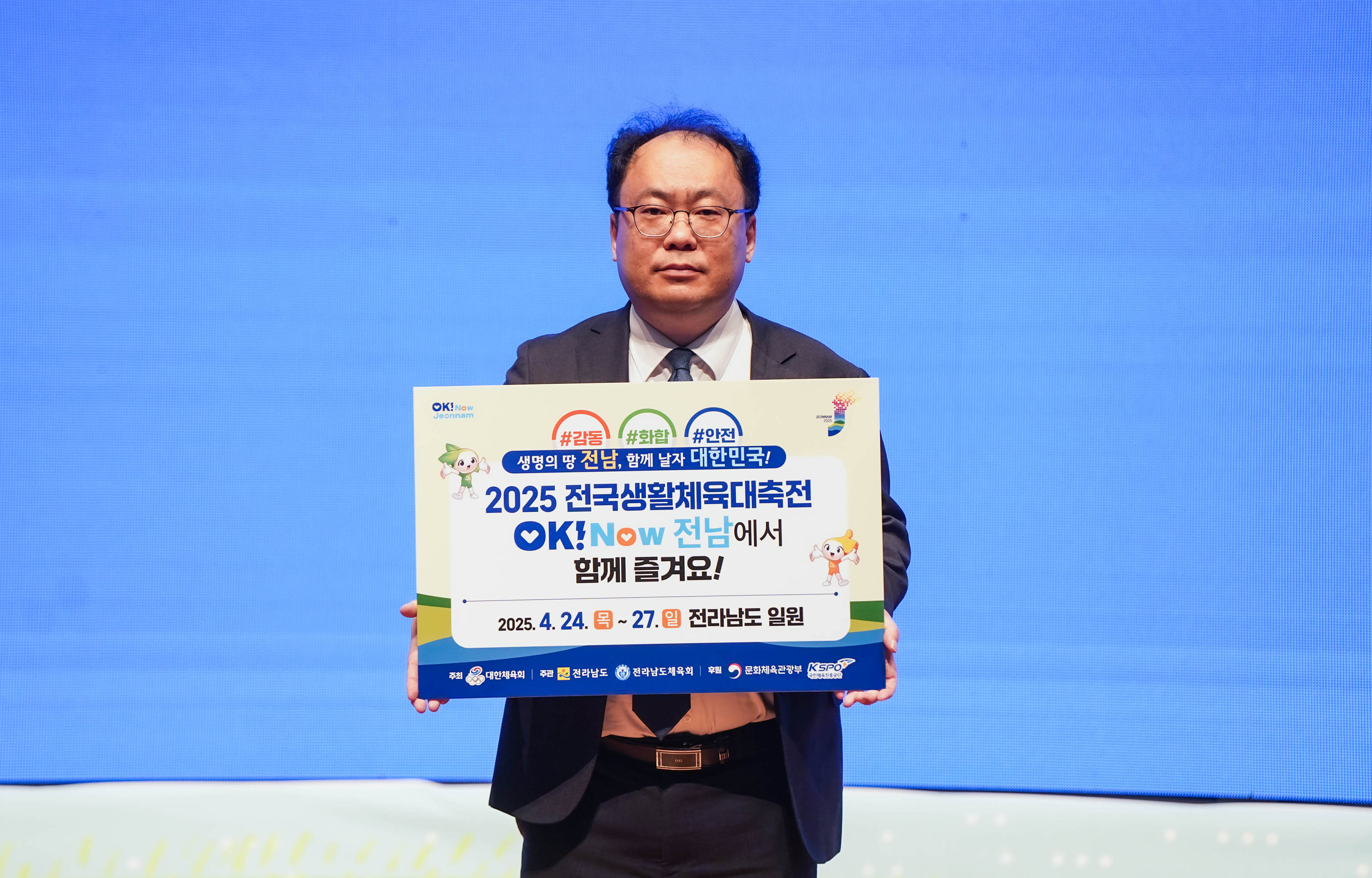 '#감동 #화합 #안전
생명의 땅 전남, 함께 날자 대한민국!
2025 전국생활체육대축전
OK! Now 전남에서
함께 즐겨요!
2025.4.24.목~27.일 전라남도 일원' 문구가 적힌 팻말을 든 관계자의 모습