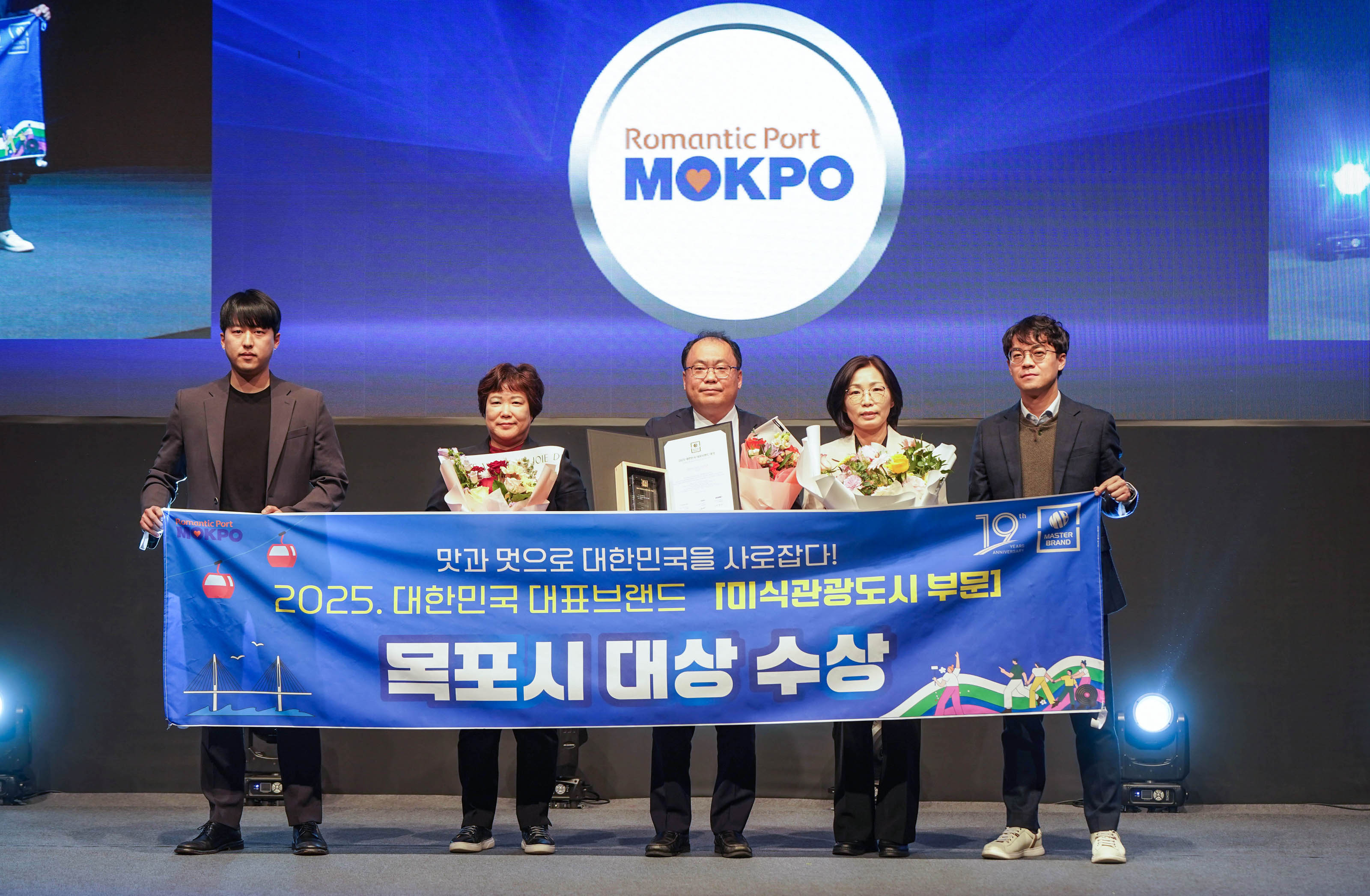 대한민국 대표브랜드대상 미식관광도시부문을 수상한 목포시의 관계자들이 현수막(맛과 멋으로 대한민국을 사로잡다! 2025대한민국 대표브랜드 미식관광도시 부문 목포시대상수상)을 들고 기념촬영을 하는 모습