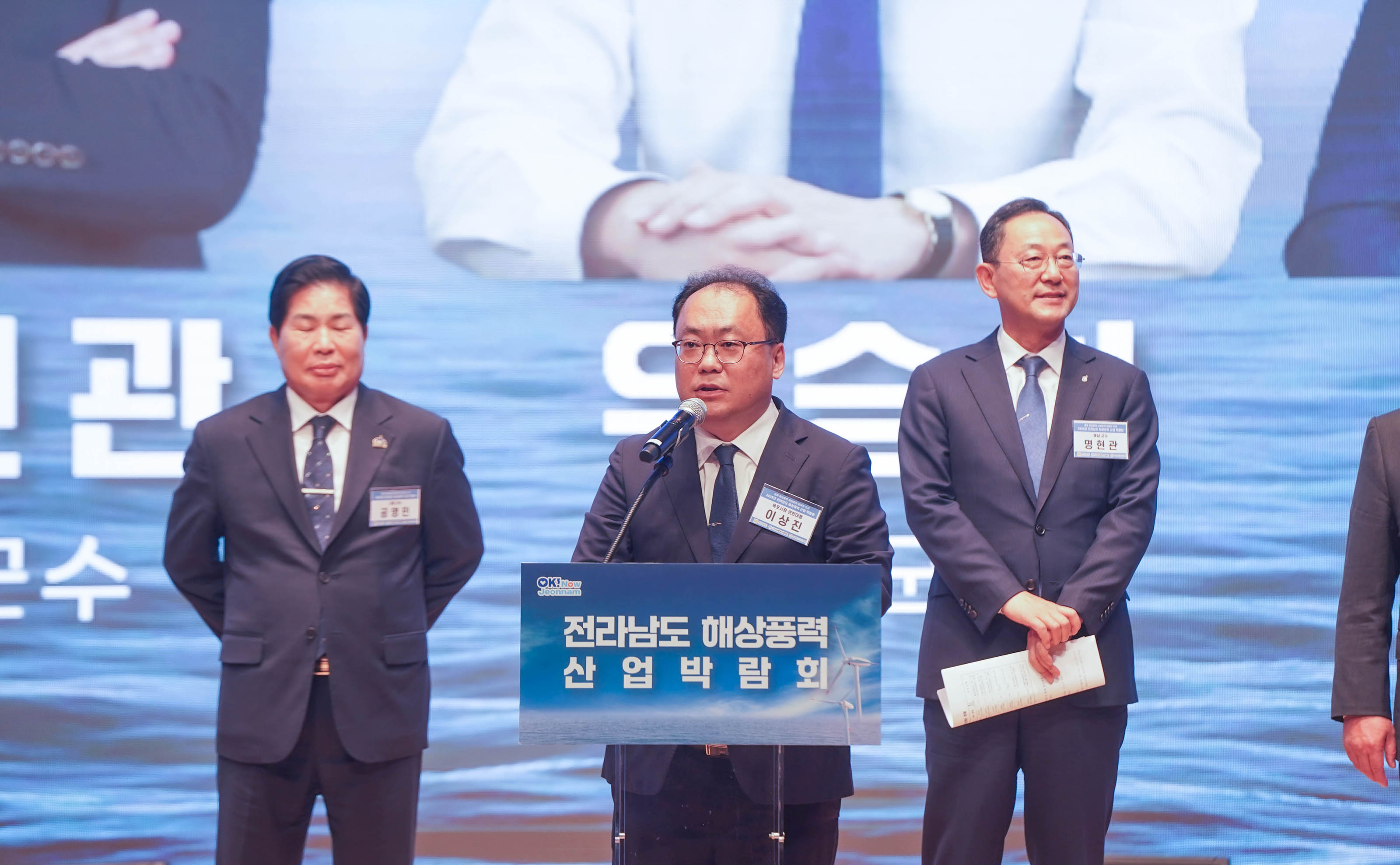 박람회 연단에서 축사를 하고 있는 이상진 목포시 권한대행의 모습. 뒤편으로 내빈들이 서 있음.