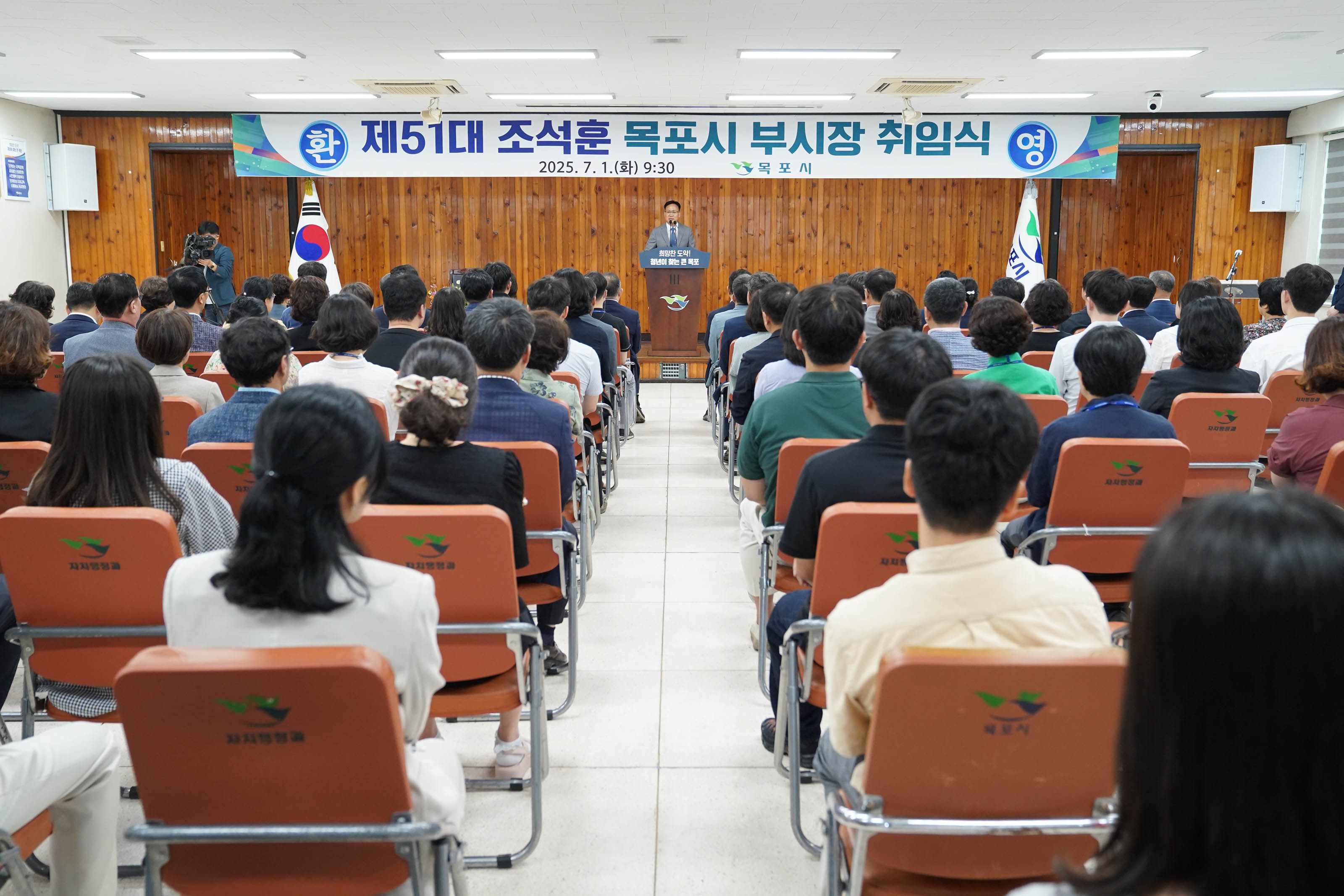 행사장 뒷모습. '제51대 조석훈 목포시 부시장 취임식' 현수막이 걸린 단상을 향해 많은 직원이 의자에 앉아 조석훈 부시장의 강연을 경청하고 있는 모습.