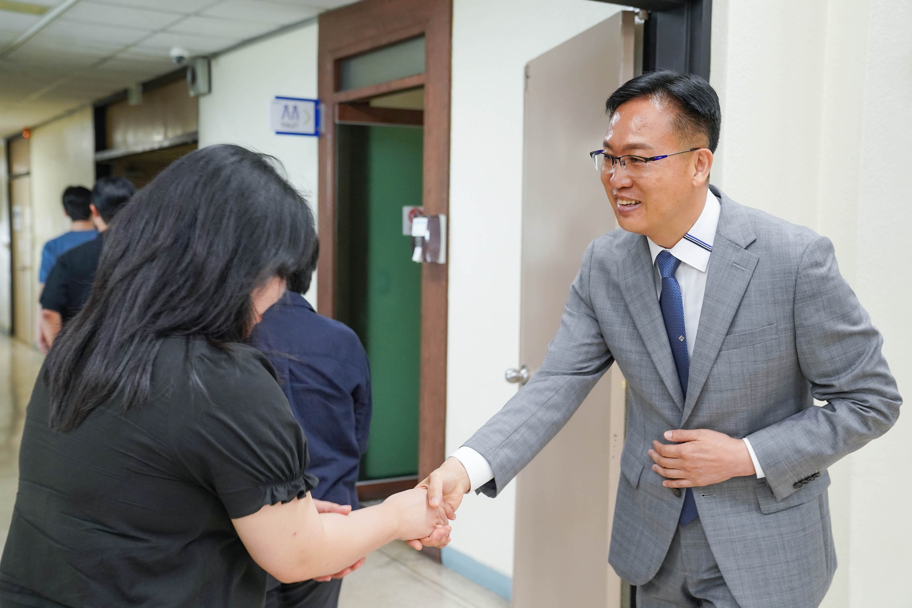 복도에서 조석훈 부시장이 한 손을 배에 올리고 정중하게 웃으며 여성 직원과 악수를 나누는 모습.