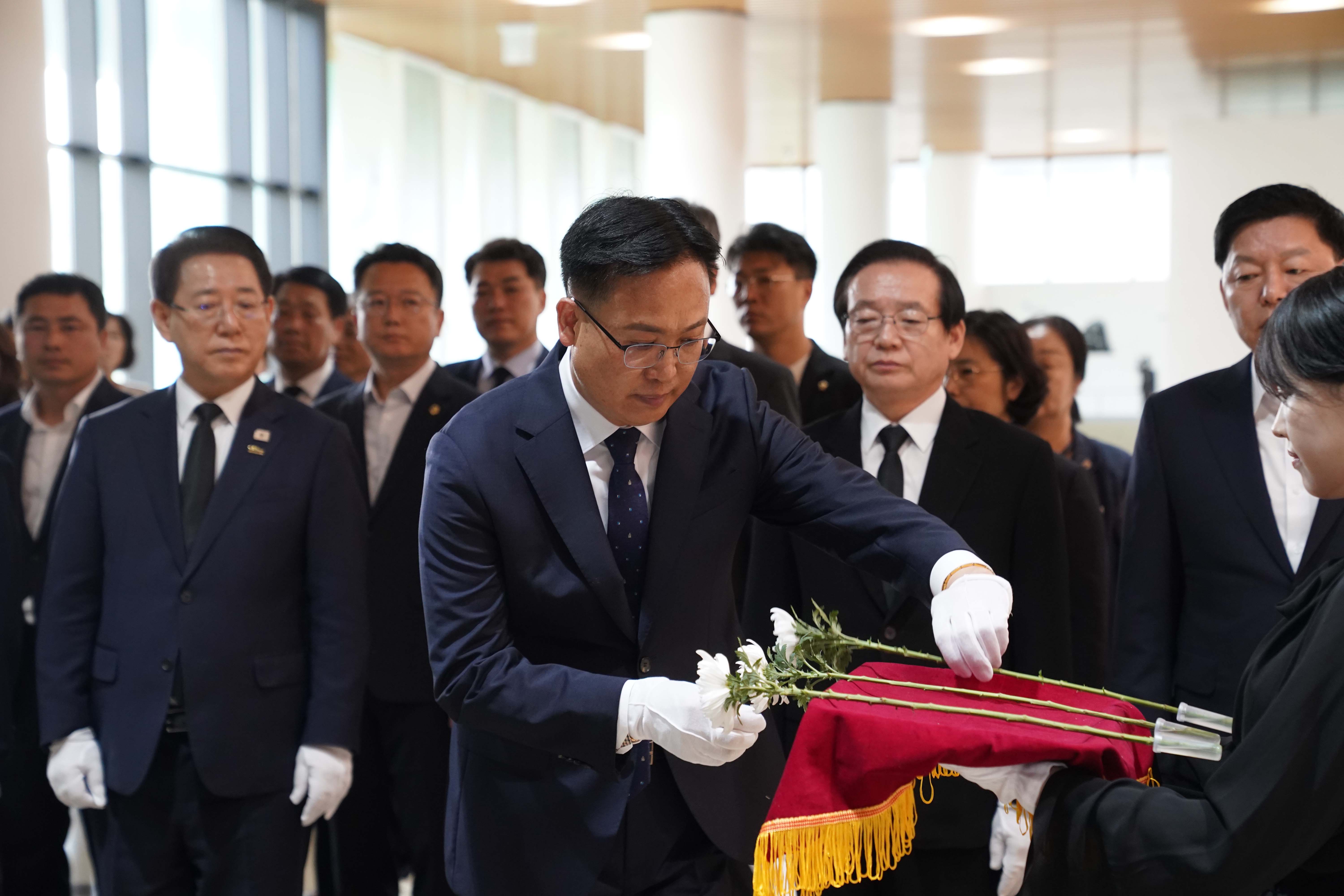 김대중 대통령 서거 16주기 추모식에서 흰 장갑을 낀 내빈이 헌화용 국화꽃을 전달받고 있는 모습.