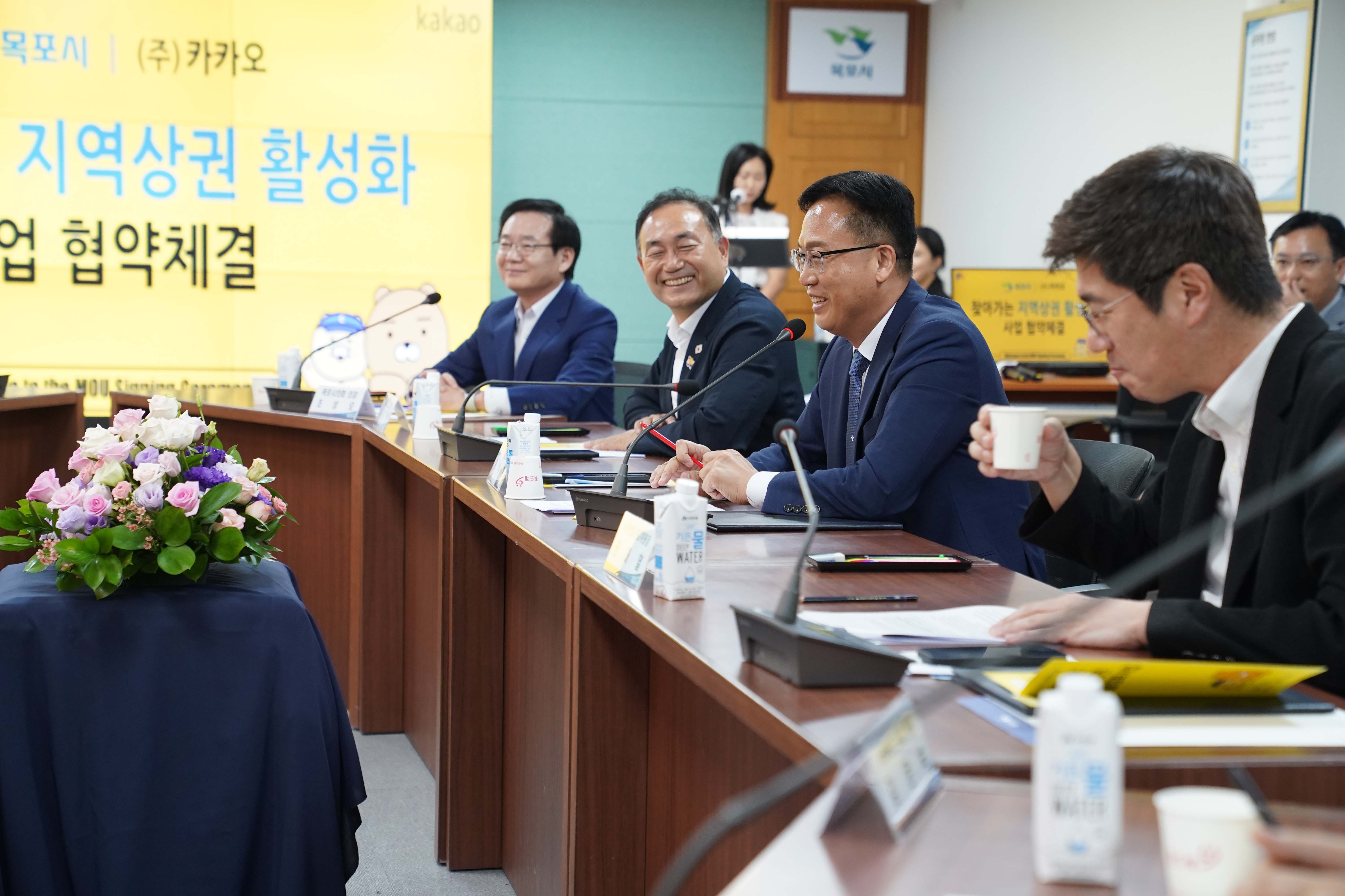회의 중 목포시 관계자들이 밝게 웃으며 대화하는 모습. 배경 스크린에는 '찾아가는 지역상권 활성화 사업 협약체결' 문구와 카카오프렌즈 캐릭터(라이언, 춘식이)가 보임.