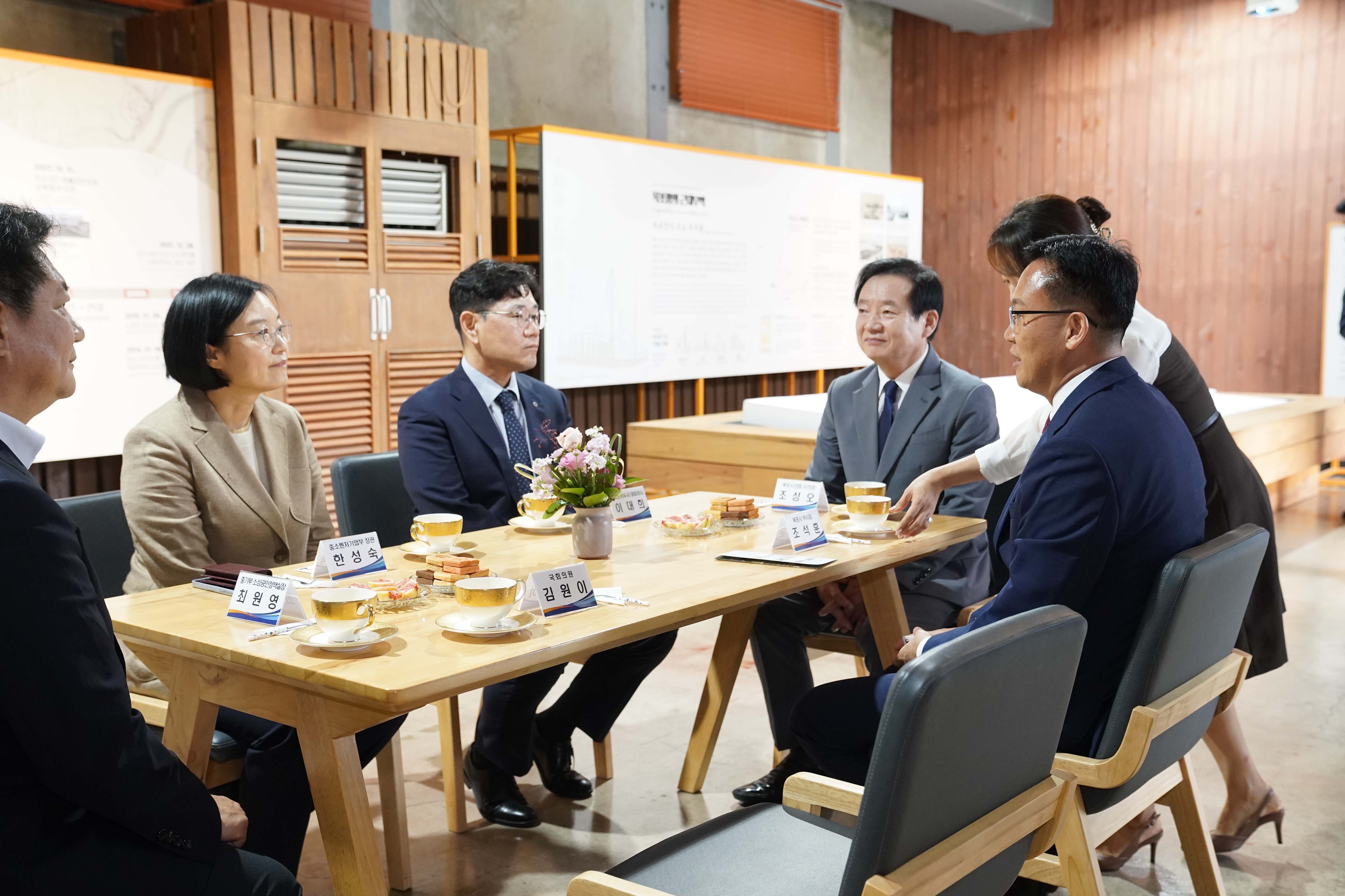 실내 회의장에서 한성숙 장관, 김원이 국회의원 등 주요 인사들이 원형 테이블에 앉아 차를 마시며 담소를 나누는 모습. 테이블 위에는 최원영, 한성숙, 김원이, 이대희, 조상오, 조석훈 등의 명패가 놓여 있음.