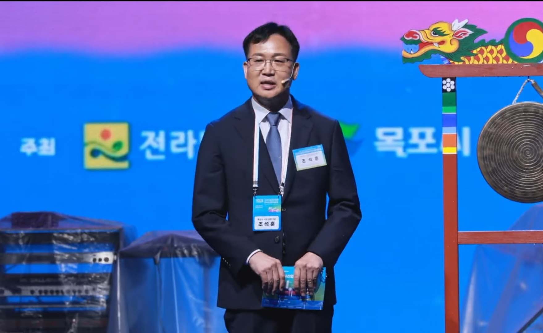행사 무대 위에서 발언 중인 조석훈 목포시장 권한대행의 상반신 모습. 배경에 주최 기관인 '전라남도', '목포시' 로고가 보이며 우측에는 용 장식이 된 징이 놓여 있음.