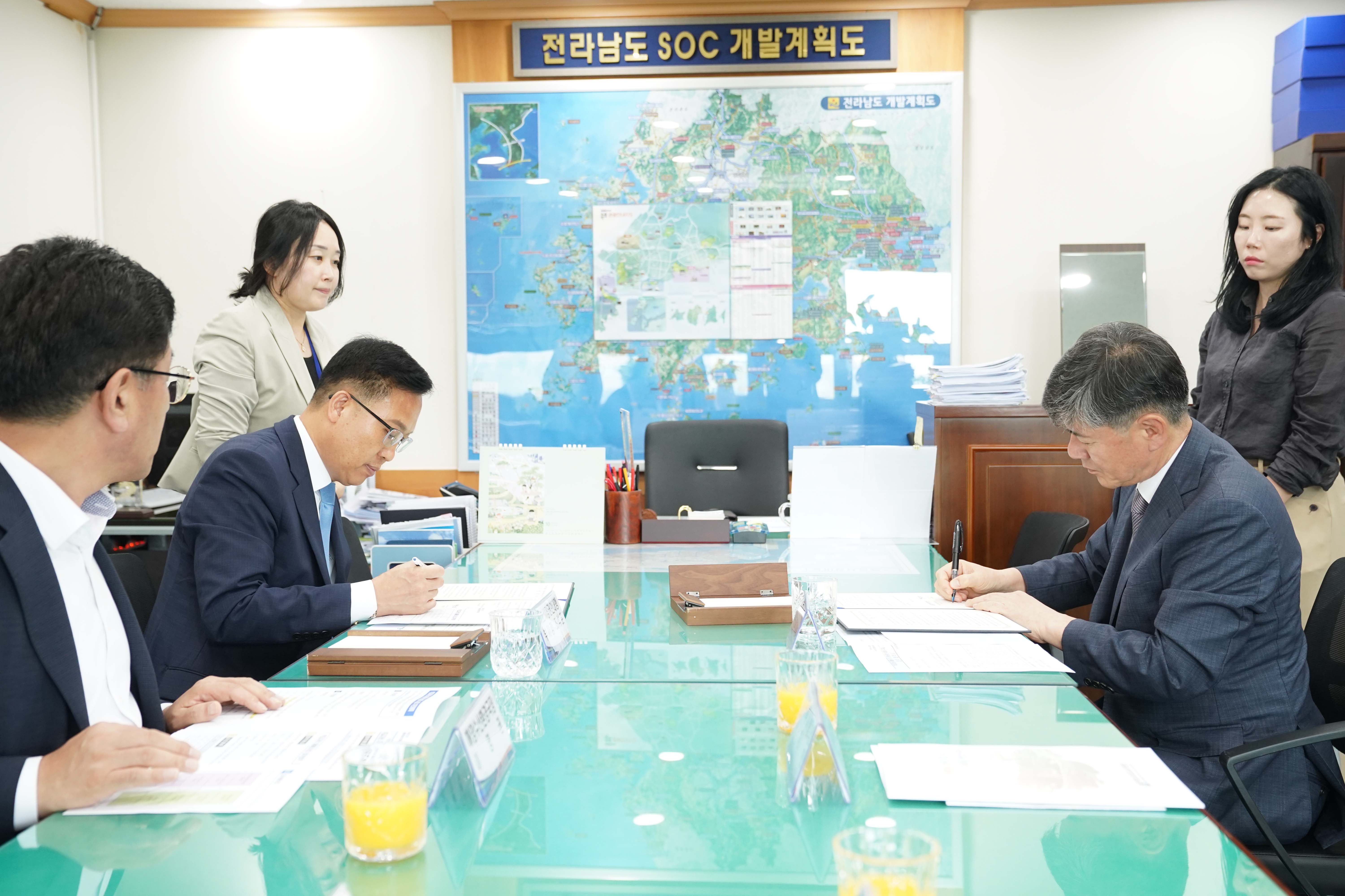 조석훈 부시장과 정덕원 교육장이 '전라남도 SOC 개발계획도' 지도를 배경으로 나란히 앉아 각각 업무 협약서에 서명하고 있는 모습.