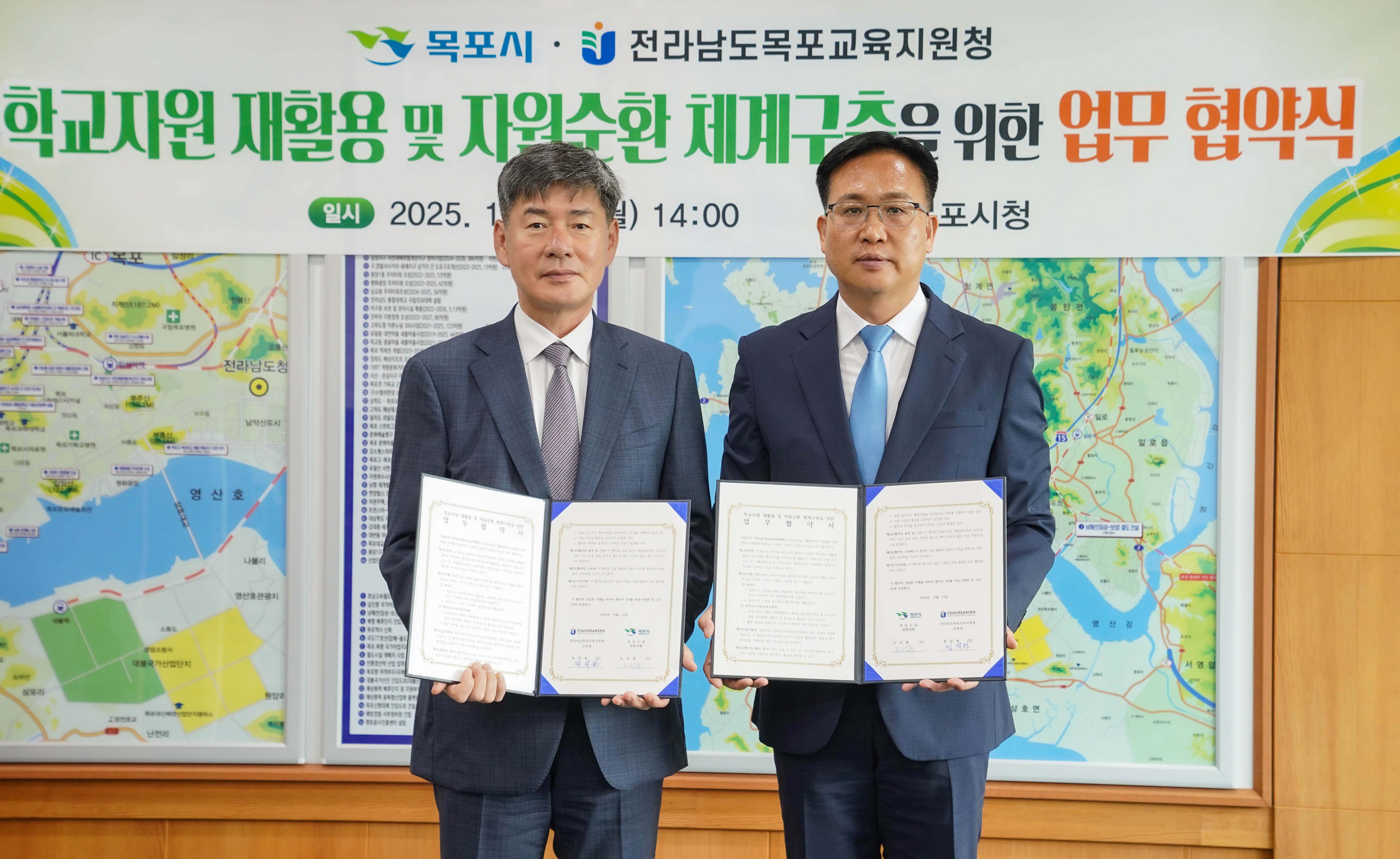 정덕원 교육장과 조석훈 부시장이 서명을 마친 '학교자원 재활용 및 자원순환 체계구축을 위한 업무 협약서'를 각각 펼쳐 들고 정면을 응시하며 기념 촬영을 하는 모습. 상단에는 목포시와 전라남도목포교육지원청 로고가 들어간 행사 현수막이 보임.