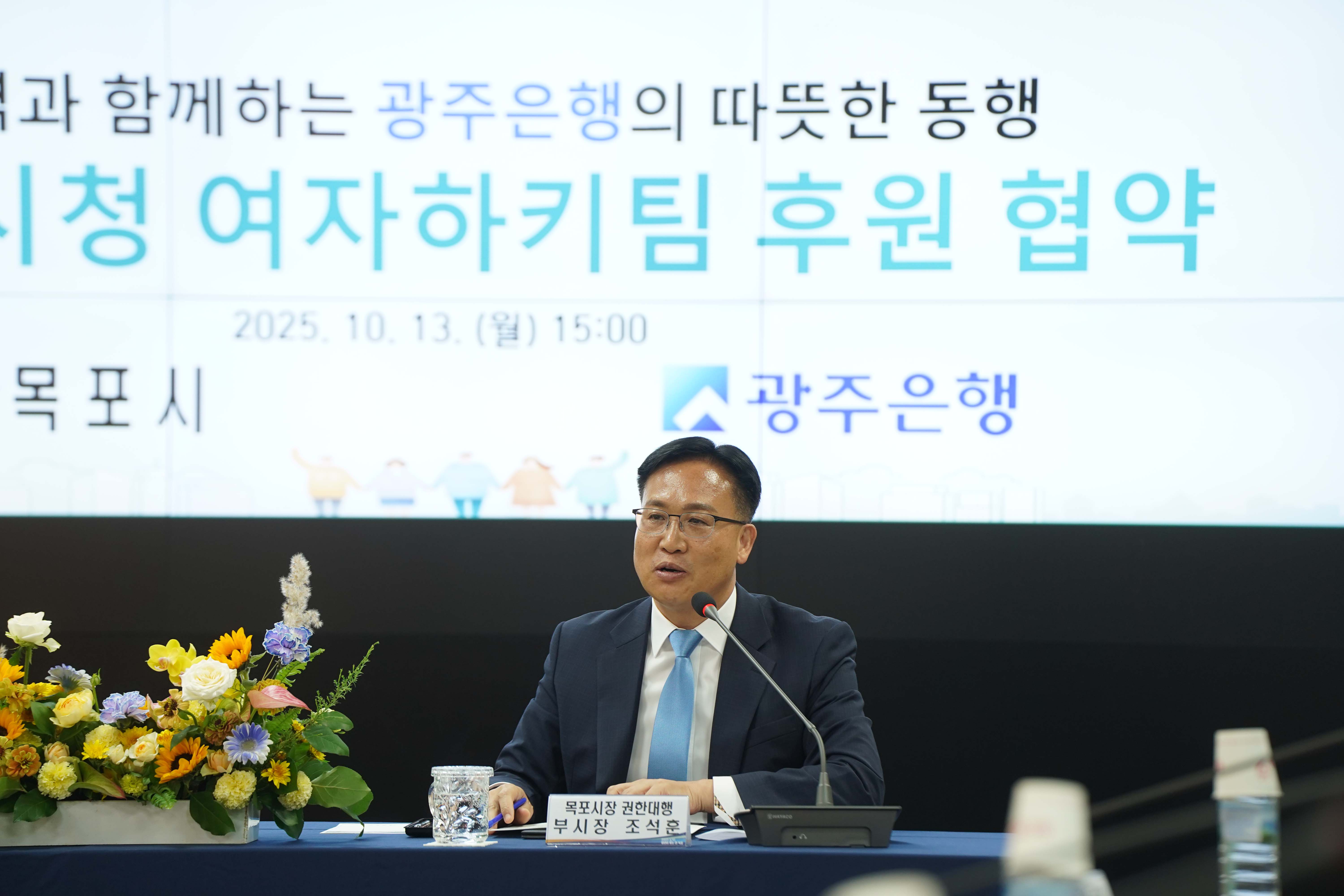 협약식에서 발언 중인 조석훈 목포부시장. 앞에는 '목포시장 권한대행 부시장 조석훈' 명패가 놓여 있으며 배경에 '따뜻한 동행', '광주은행' 문구가 보임.