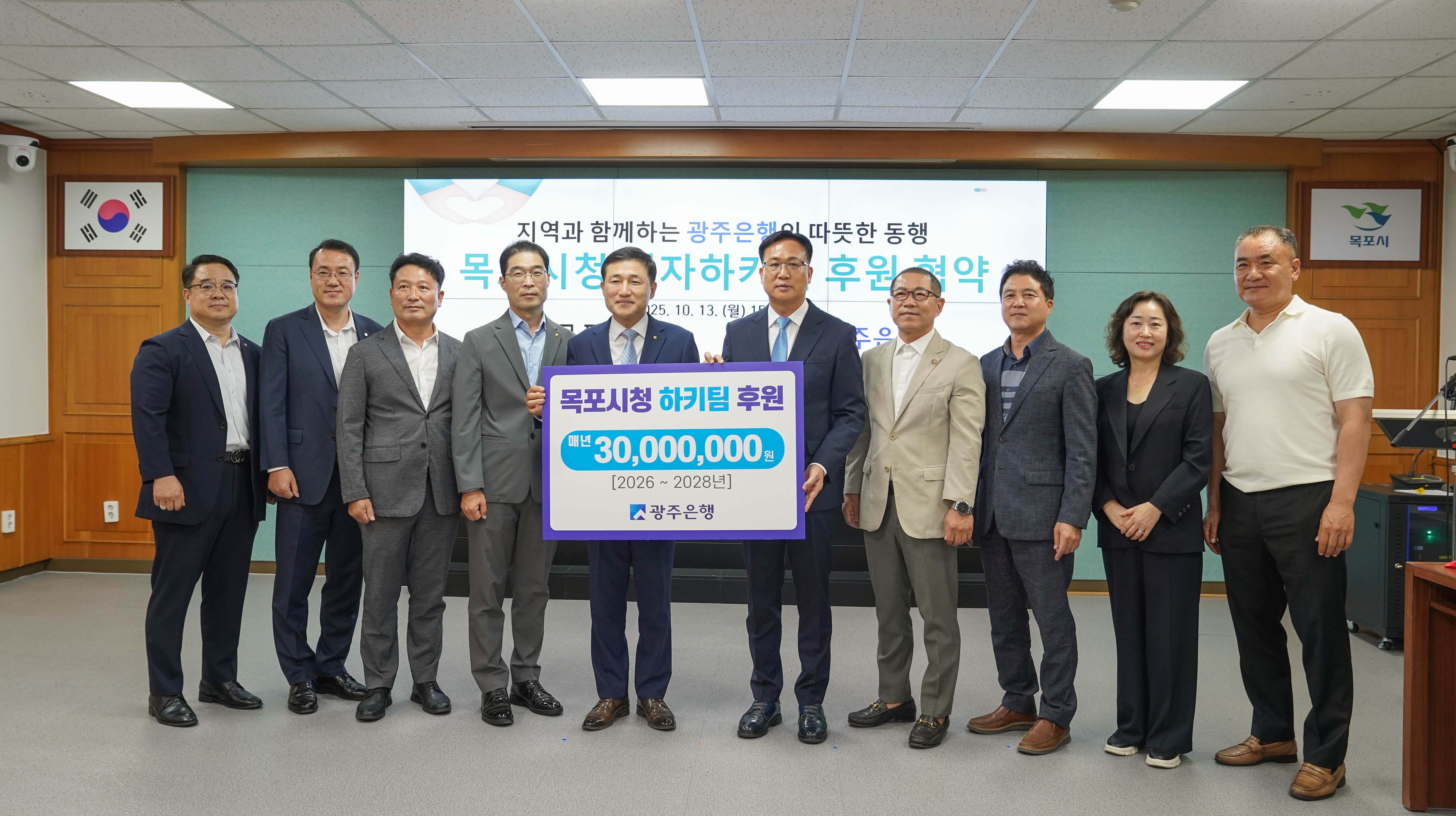 후원 협약식 단체 기념사진. 관계자들이 함께 '목포시청 하키팀 후원 매년 30,000,000원 (2026~2028년) 광주은행'이라고 적힌 대형 판넬을 들고 있음.