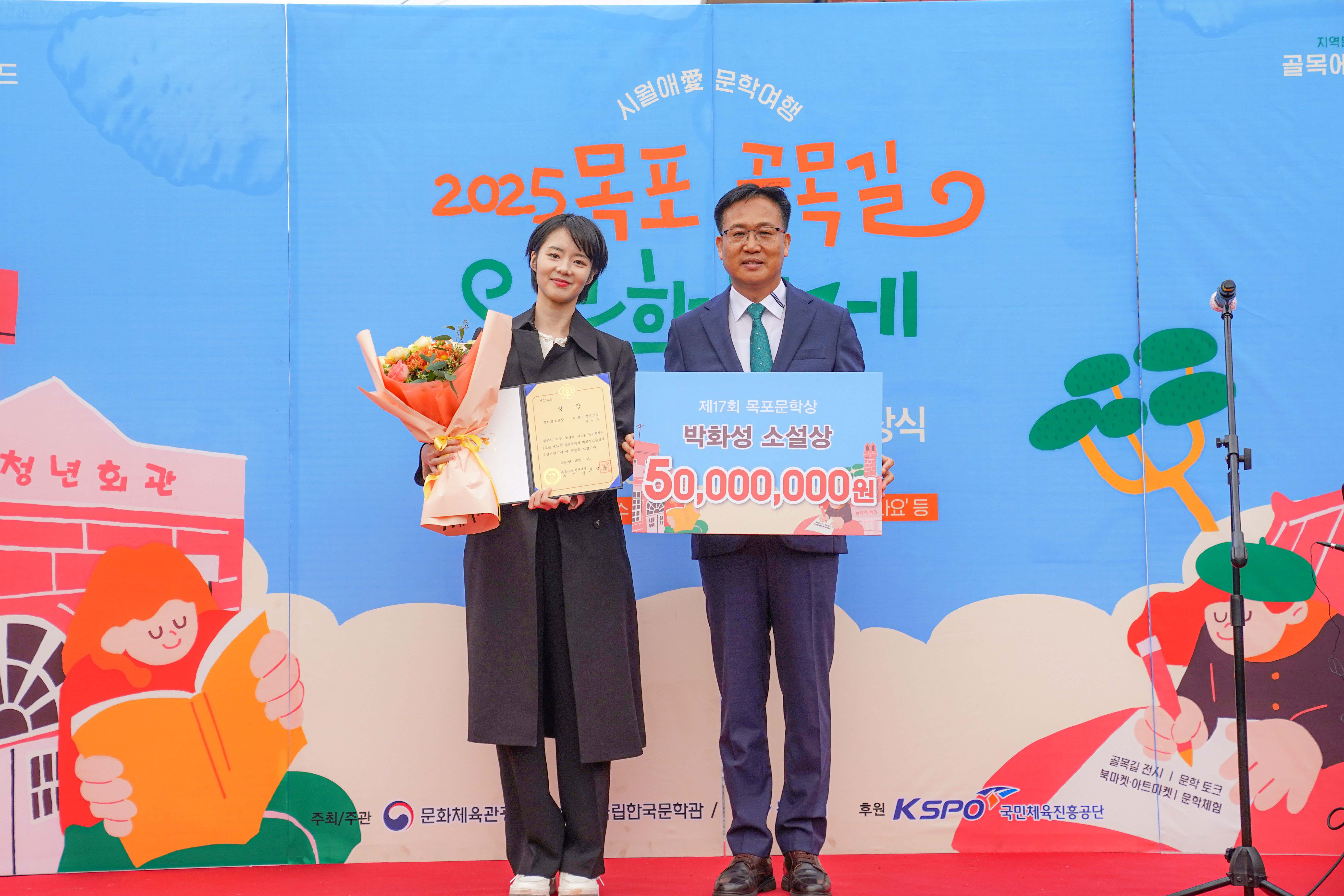 제17회 목포문학상 시상식 기념 촬영. 조석훈 목포부시장이 '박화성 소설상 50,000,000원' 판넬을 수상자와 함께 들고 있으며, 수상자는 꽃다발과 상장을 들고 있음.