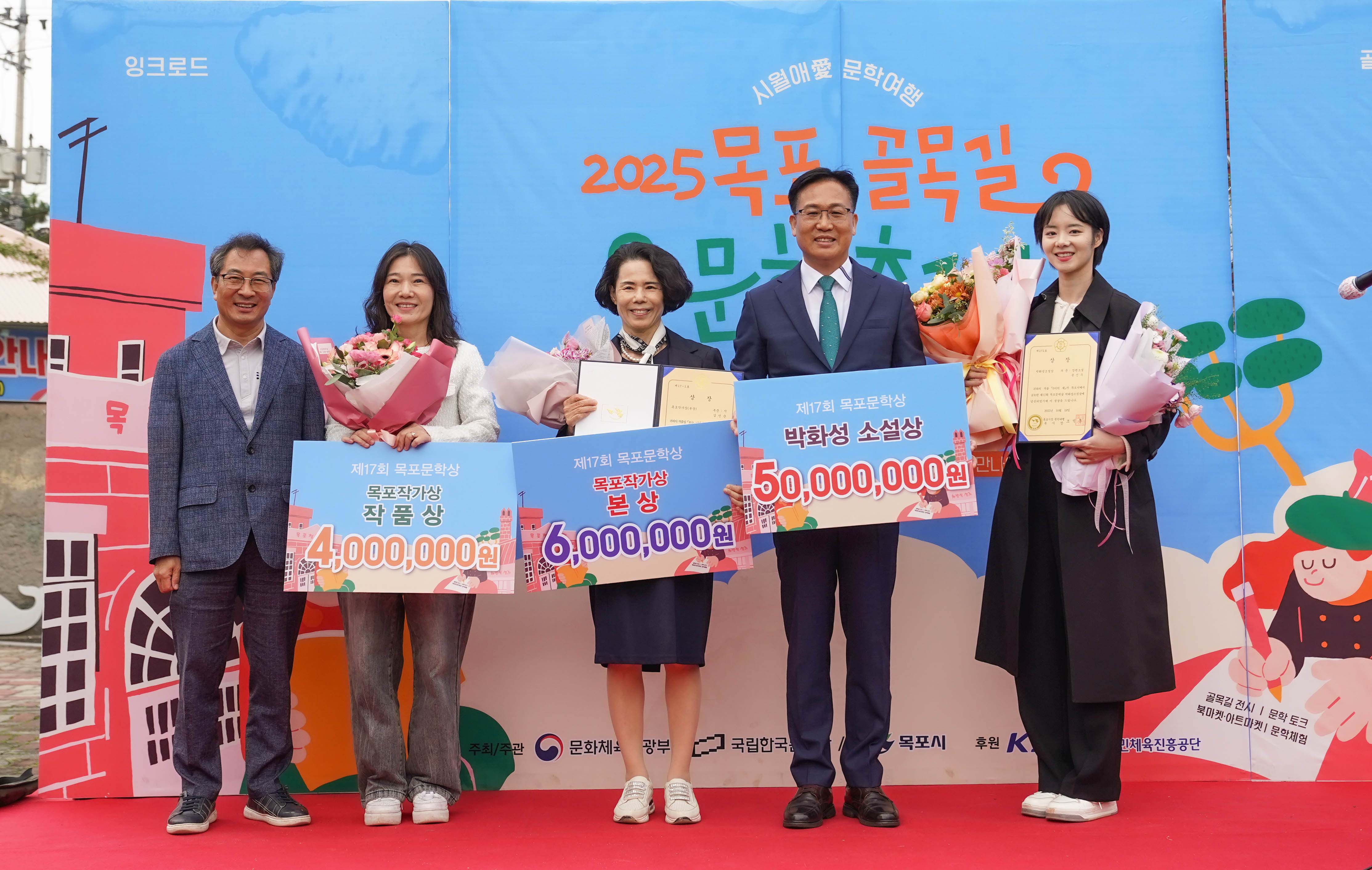 목포문학상 전체 수상자 기념 촬영. '박화성 소설상 50,000,000원', '목포작가상 본상 6,000,000원', '목포작가상 작품상 4,000,000원' 판넬을 든 내빈과 수상자들이 무대 위에서 함께 포즈를 취하고 있음.
