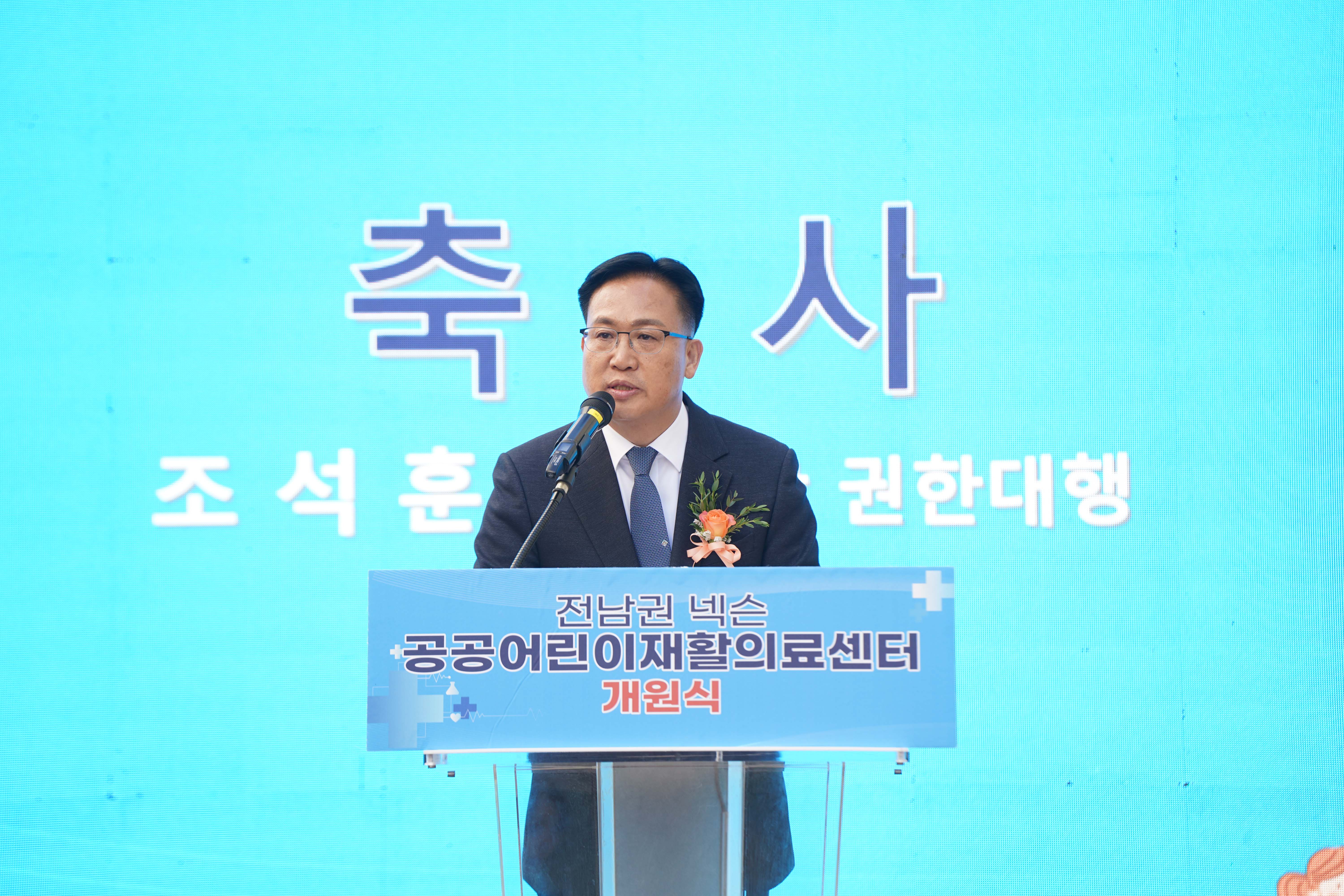 축사 중인 조석훈 목포시장 권한대행의 상반신 모습. 단상에는 '전남권 넥슨 공공어린이재활의료센터 개원식' 문구가 부착되어 있음.