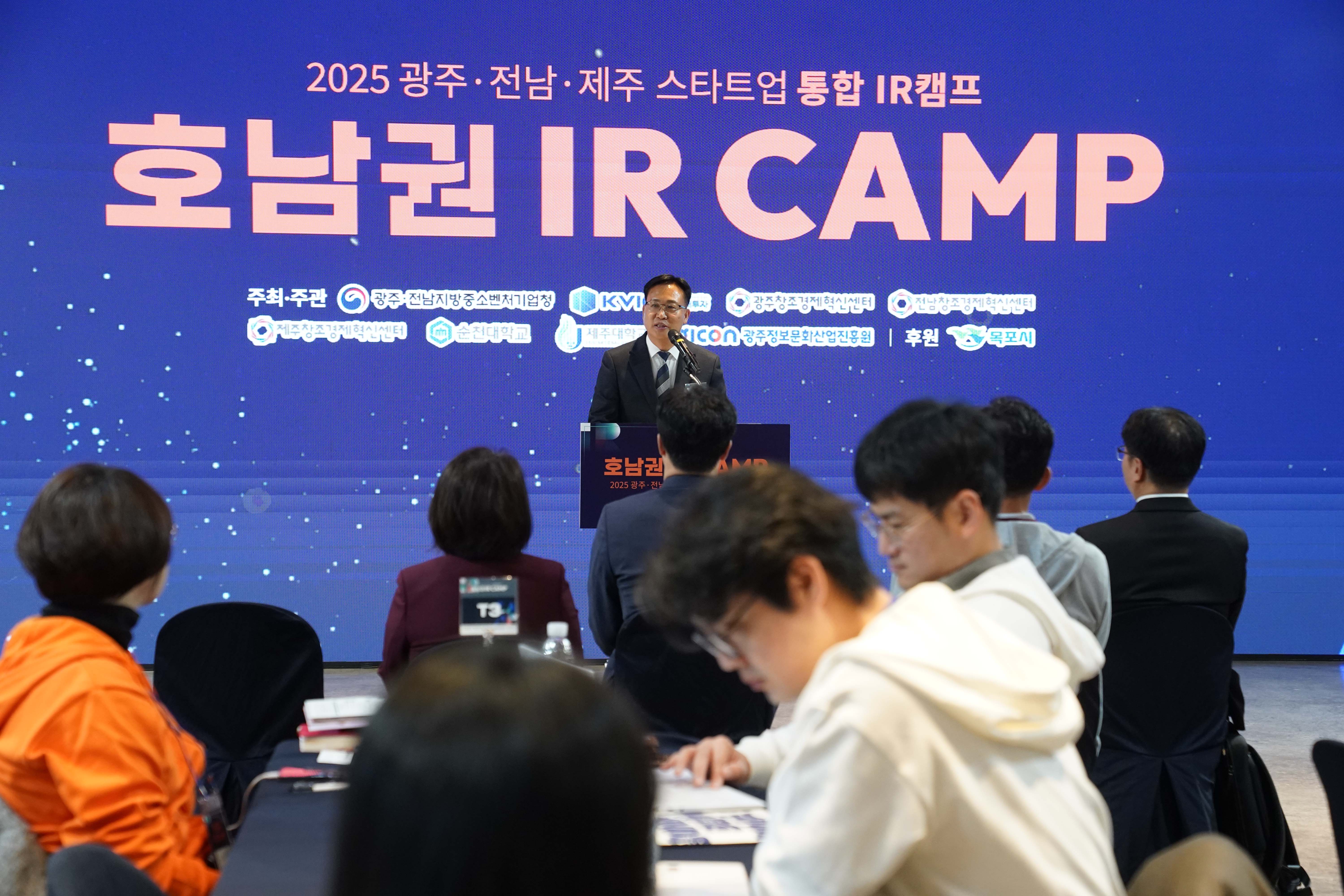 '호남권 IR CAMP' 메인 스크린 앞에서 조석훈 부시장이 마이크를 잡고 축사를 하고 있는 모습. 앞쪽 테이블에는 참가자들이 앉아 행사를 경청하고 있음.