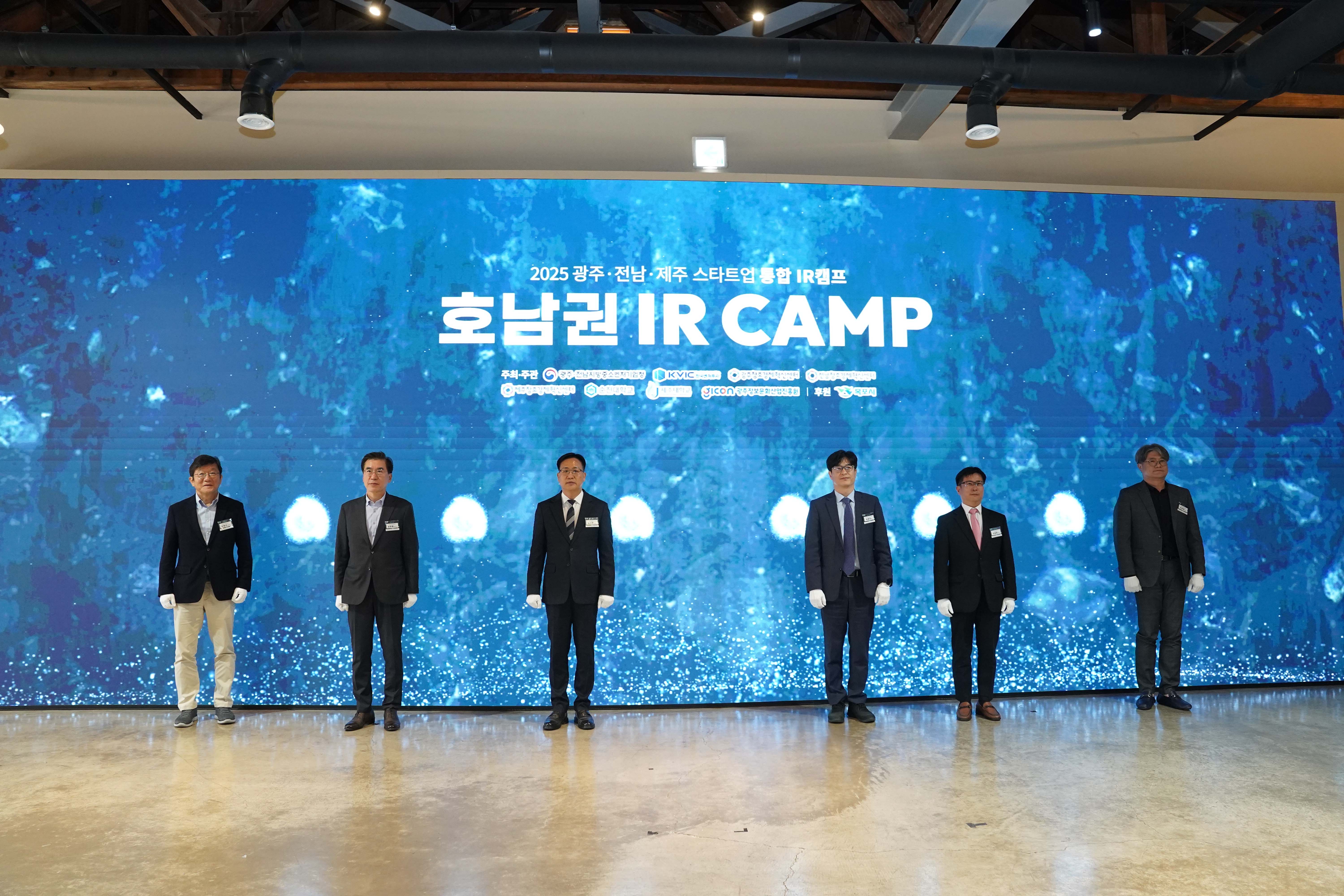 화려한 푸른색 미디어 월을 배경으로 '2025 광주·전남·제주 스타트업 통합 IR캠프 호남권 IR CAMP' 문구 아래 주요 내빈 6명이 나란히 서서 기념 촬영을 하는 모습.